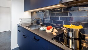 Eine moderne Küche mit dunkelblauen Schränken, einer Edelstahl-Spüle und einer schwarzen Arbeitsplatte.