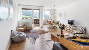 Ein geräumiges Wohnzimmer mit großem Fenster, Essbereich und einer gemütlichen Sitzecke.