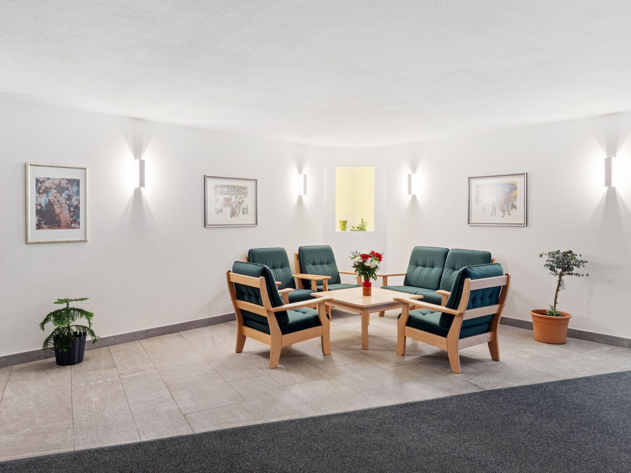 Een kamer met een ronde tafel, vier stoelen en een kamerplant.