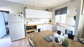 Een koelkast, een magnetron, een vaatwasser, kookgerei, borden en bestek