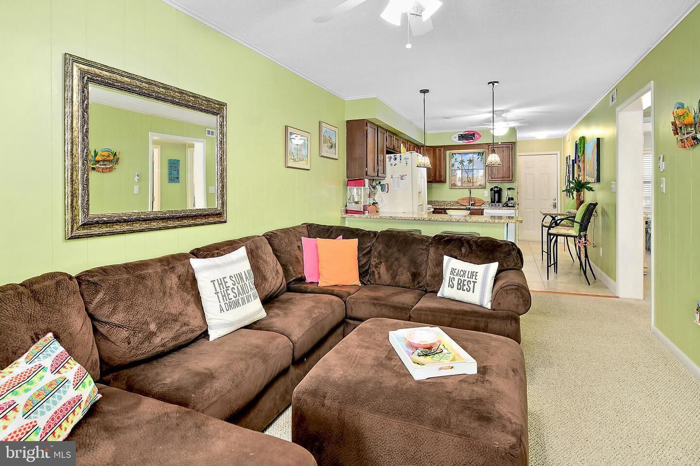 A living room with a sectional sofa, a dining area with a table and chairs, and a kitchen in the background.