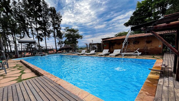 A swimming pool with wooden deck, lounge chairs, and a gazebo. - Ranchos 30 Hotel Fazenda (Hidrolandia)