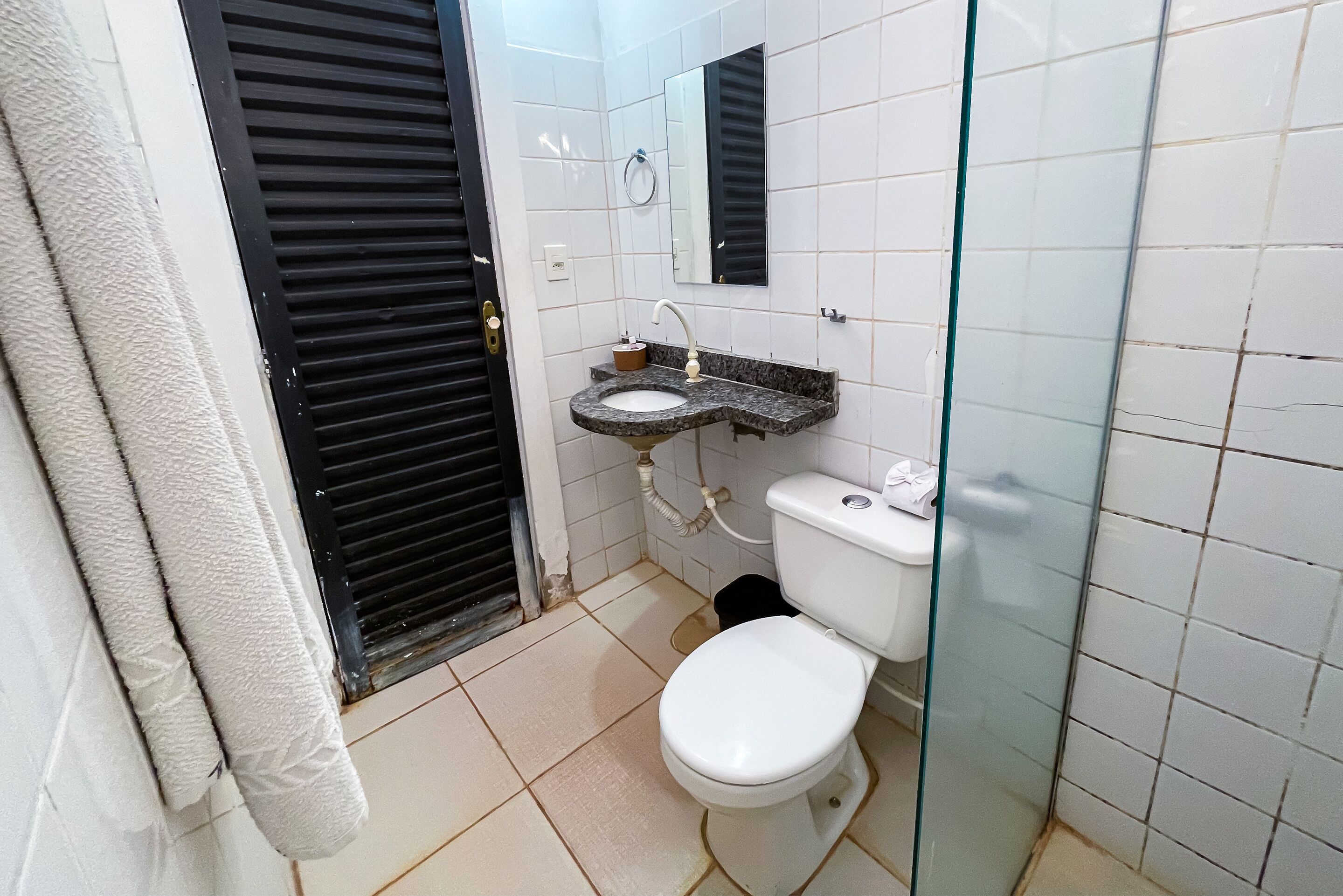 A bathroom with a toilet, sink, and mirror.