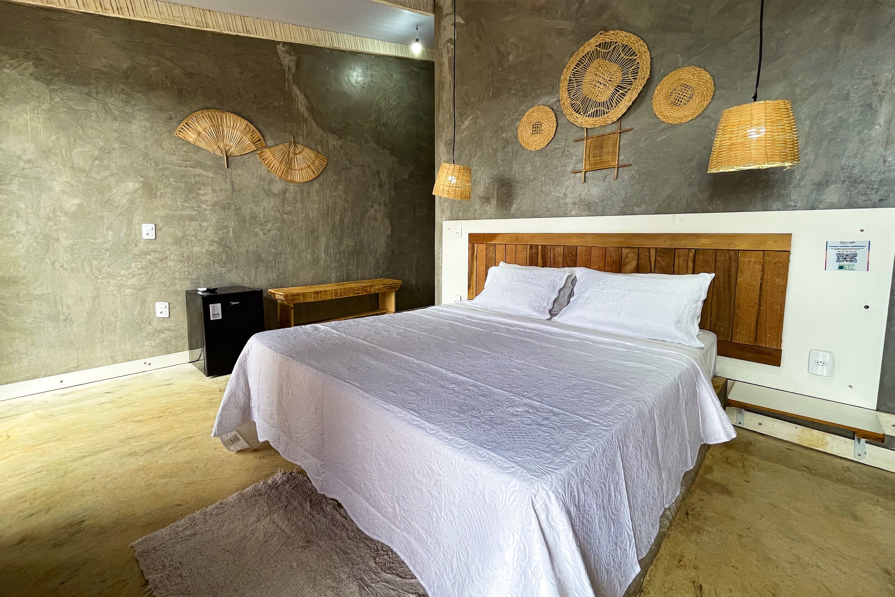 A bedroom with a wooden headboard, white bedding, and woven wall decorations.