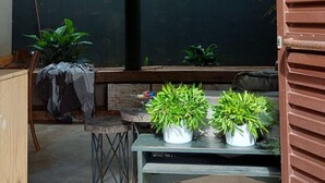 A room with a large window, a wooden cabinet, a table with potted plants, and a bench. - Ranchos 30 Hotel Fazenda (Hidrolandia)
