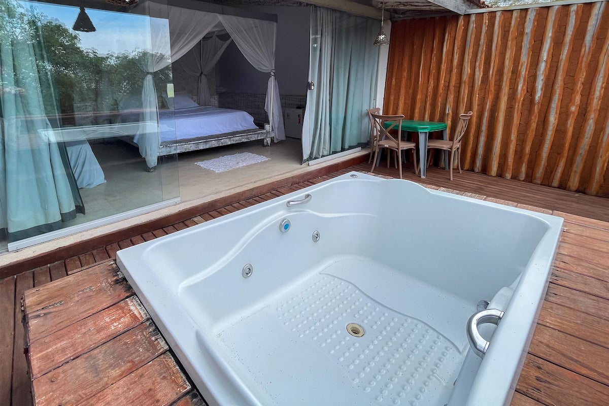 A room with a large bathtub, a bed with a canopy, and a table with chairs.