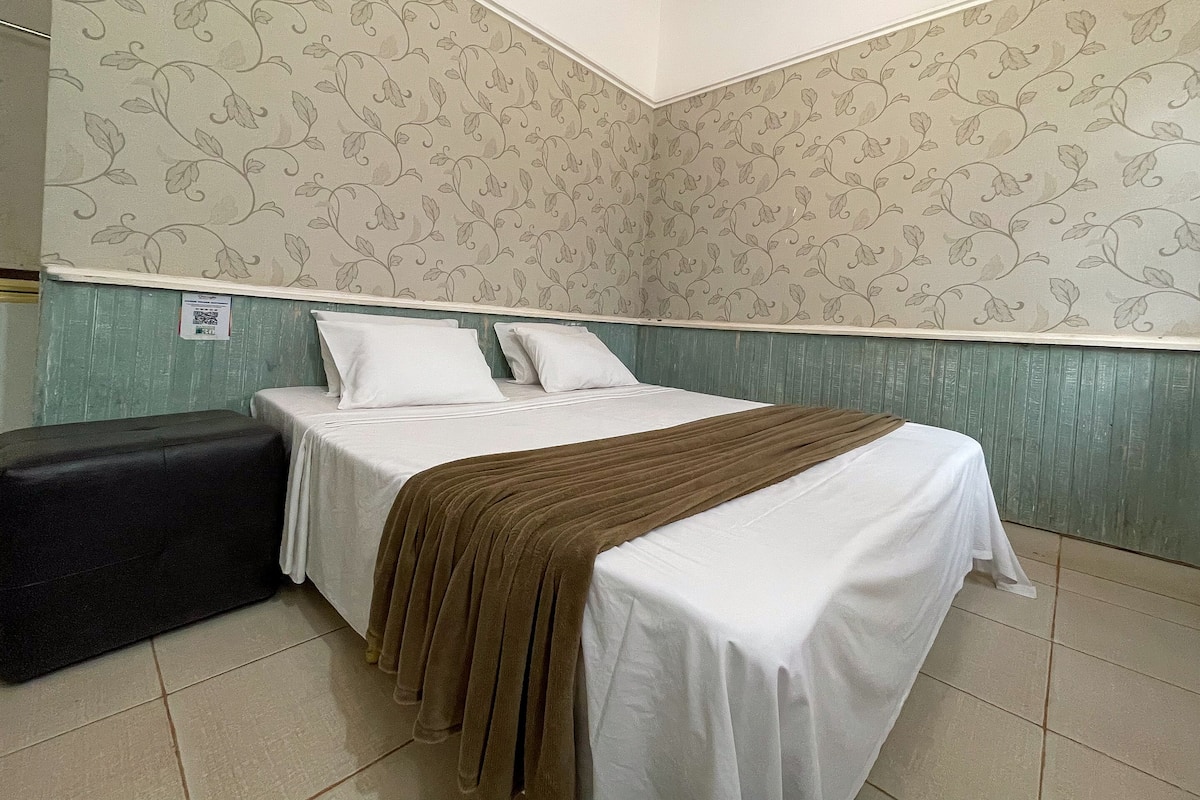 A room with a bed, a bench, and a patterned wall.