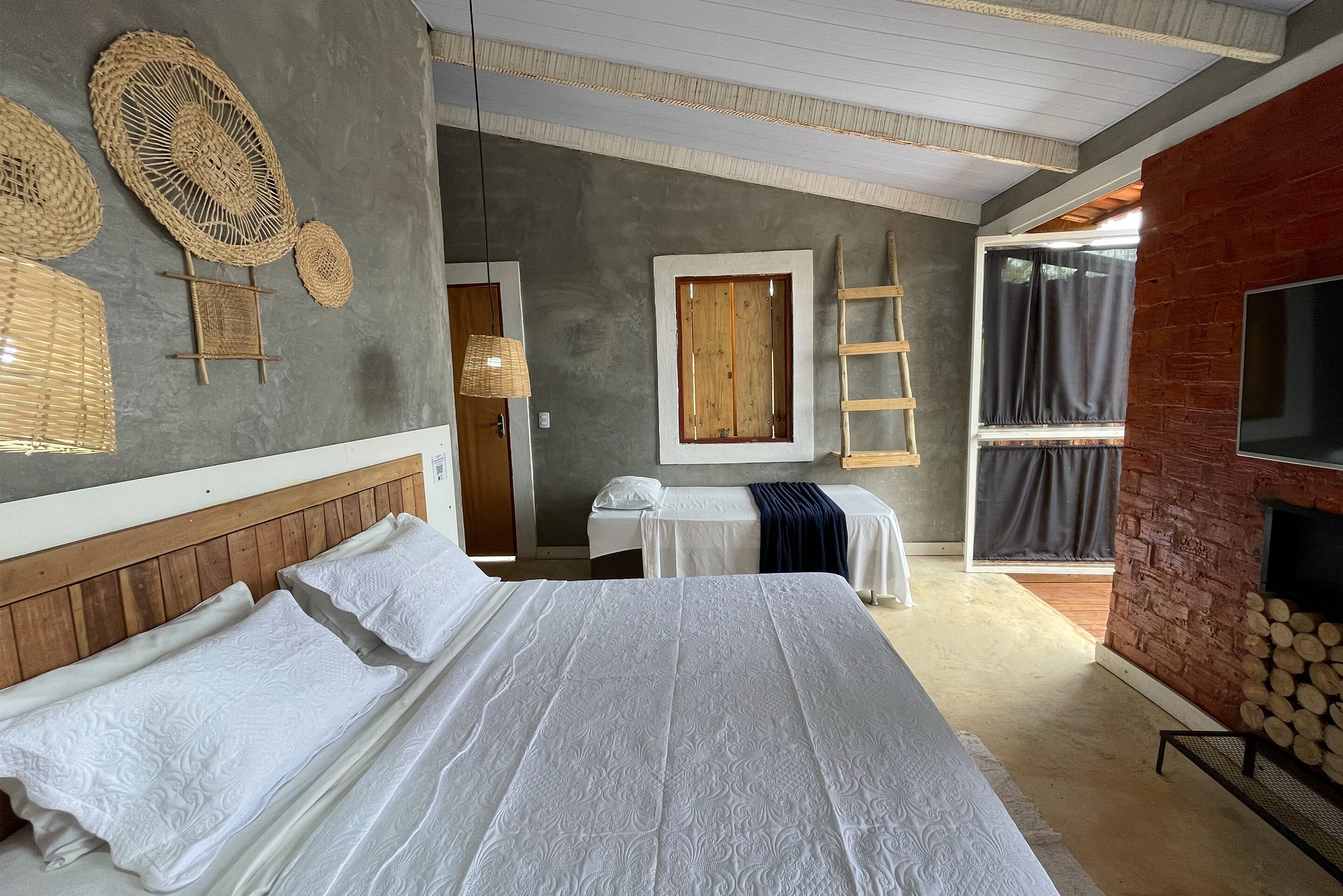 A bedroom with a bed, a wooden ladder, a TV, and a fireplace.