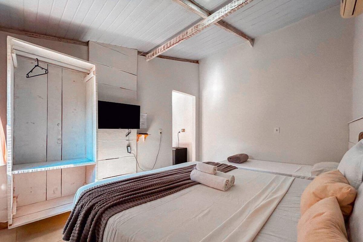 A bedroom with a bed, a bedside table, a mirror, and a wardrobe.