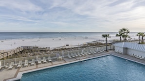 Un espace piscine avec des chaises longues et vue sur la plage.