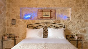 A bed with white linens in a room with stone walls and a metal headboard. - Sea View Nisaki Villa with private pool! (Zakynthos)