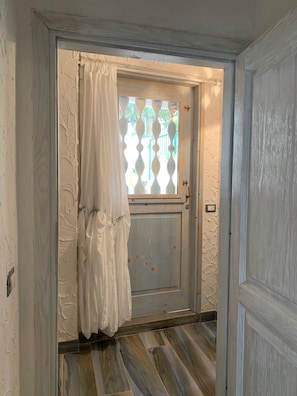 Une porte avec une fenêtre, un rideau blanc et un mur à texture.