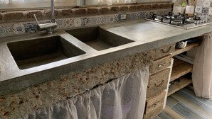 A kitchen with two sinks, a gas stove, and a window with sheer curtains. - Casetta Ale 20 mt from the sea (Tancau Sul Mare)