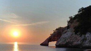 A coastal sunset with a rock formation and calm sea. - Casetta Ale 20 mt from the sea (Tancau Sul Mare)