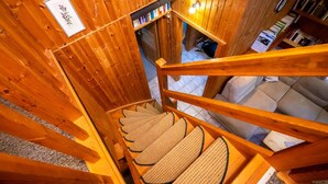 Un interior de madera con una escalera, un sofá y una estantería.