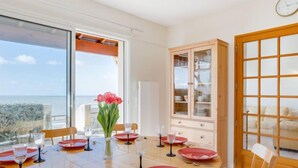 A dining area with a table set for six, a wooden cabinet, and a view of the sea. - La Grande Côte by Interhome (Saint Palais sur mer)