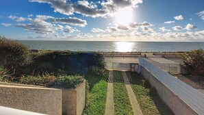 A coastal view with a clear sky, a pathway leading to a beach, and a fence along the water's edge. - La Grande Côte by Interhome (Saint Palais sur mer)