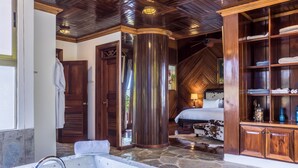 A bathroom with a stone-tiled bathtub, wooden cabinetry, and a large mirror. -  Luxury villa Playa Bonita – beachfront, private pool, chef, 7 BR, sleeps 20 (Las Terrenas)