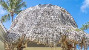 A covered outdoor area with a thatched roof, stone columns, and hanging lanterns. -  Luxury villa Playa Bonita – beachfront, private pool, chef, 7 BR, sleeps 20 (Las Terrenas)
