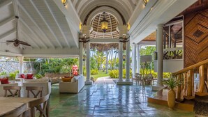 A covered outdoor area with a central pathway, white columns, and seating arrangements. -  Luxury villa Playa Bonita – beachfront, private pool, chef, 7 BR, sleeps 20 (Las Terrenas)