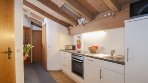 A compact kitchen with white cabinets, a microwave, a sink, and a dishwasher. - Wohnung 8 (Am Sonneneck) by Interhome (Ruhpolding)