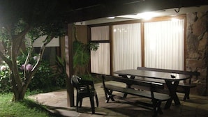 Un patio al aire libre con piso de piedra, una mesa de madera y bancos.