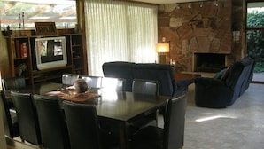 Un comedor con una mesa, sillas, televisión, chimenea y sofá.