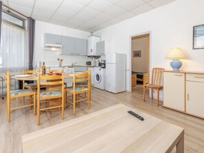 Een kleine keuken met een magnetron, koelkast en wasmachine.
