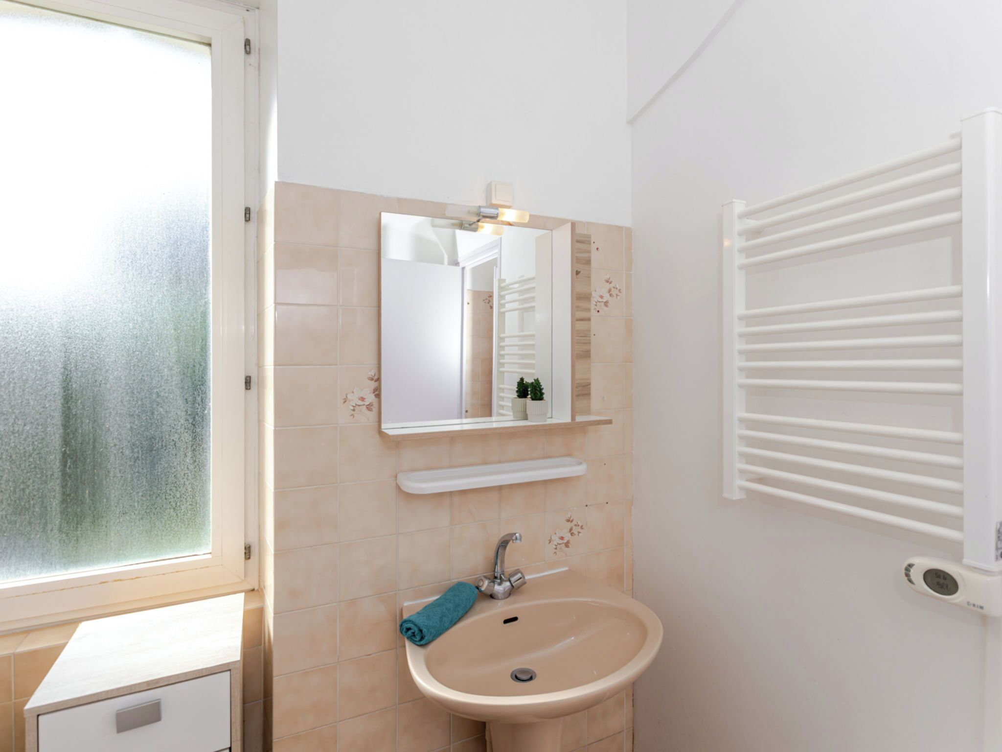 A bathroom with a sink, mirror, and towel rack.