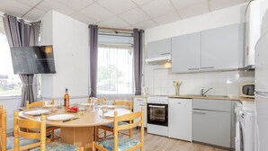 A modern kitchen with white cabinets, a built-in oven, and a microwave. - Le Petit Robinson by Interhome (Dinard)