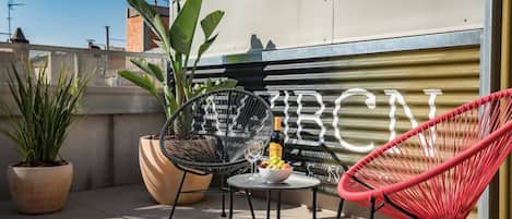 Een terras op het dak met twee stoelen, een tafel en potplanten.