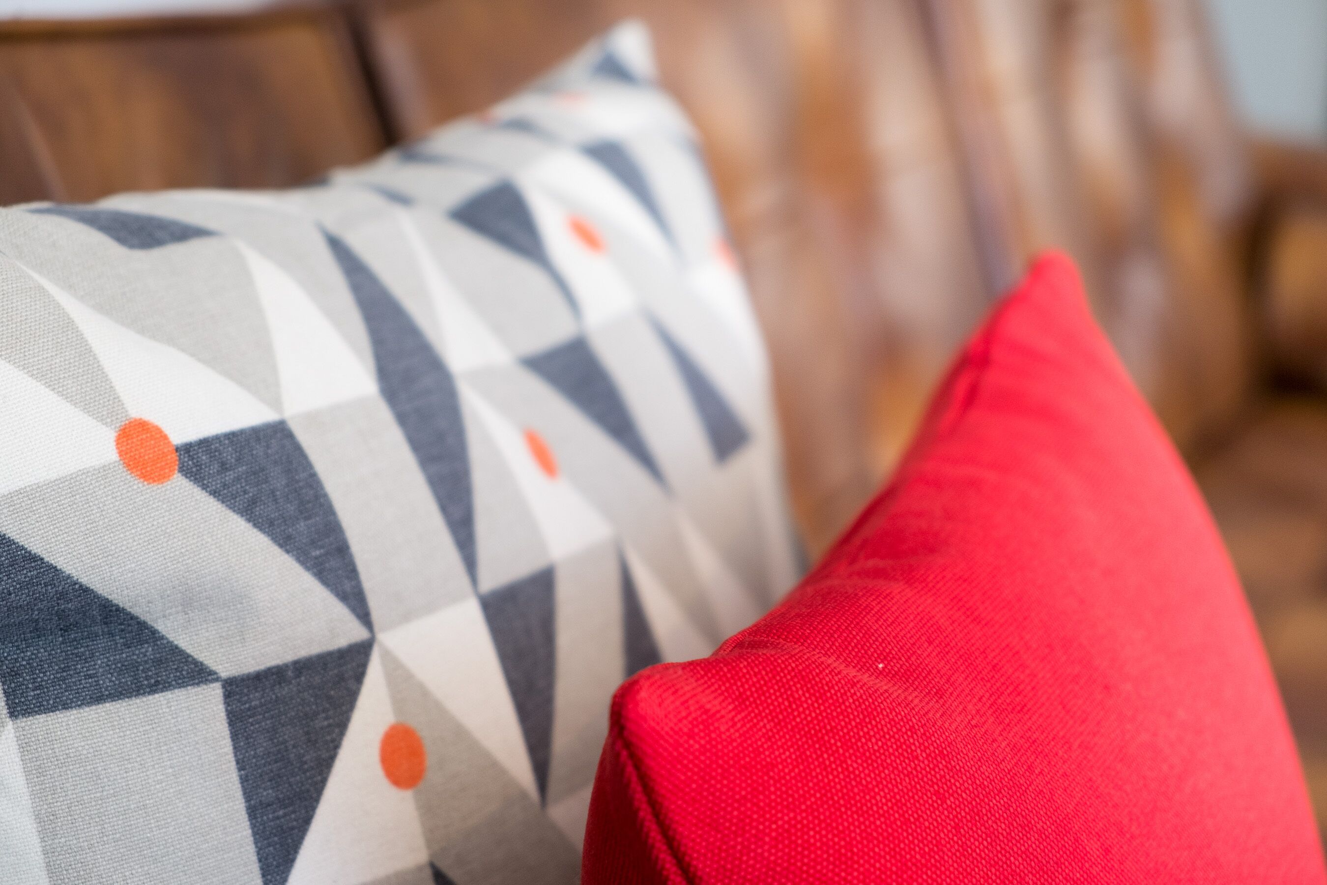 Un gros plan d’un coussin à motifs géométriques, accompagné d’un coussin rouge contrastant.