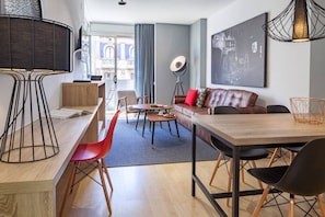A modern living room with a dining area, a sofa with cushions, a coffee table, and a bookshelf. - Hot Jazz 11 - Habitat Apartments (Barcelona)