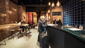 Un intérieur moderne avec des murs en briques apparentes, des luminaires suspendus et un comptoir d’accueil.