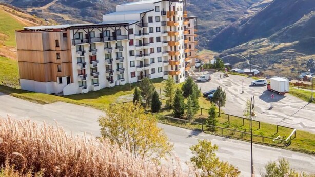 Een hotel met meerdere verdiepingen, met een modern ontwerp, gelegen in een bergachtig gebied met een parkeerplaats en uitzicht op het omliggende landschap.