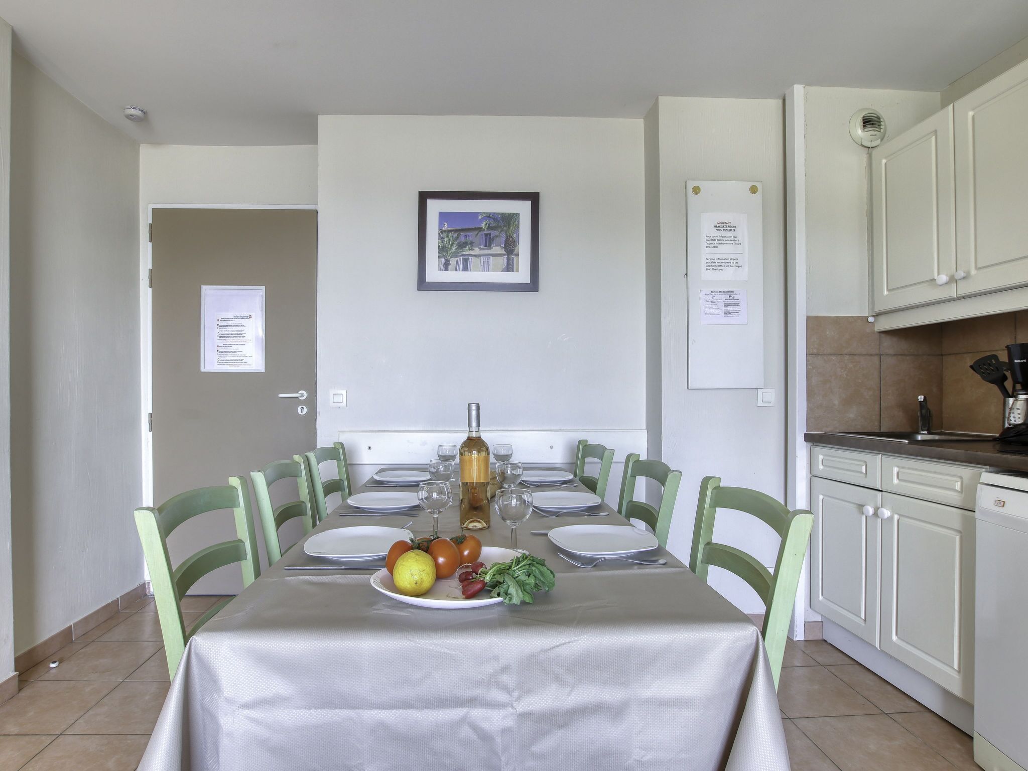 Comedor con una mesa dispuesta para seis personas, una botella de vino y un plato de fruta.