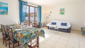 Un coin repas avec une table dressée pour deux personnes, un canapé et une petite table d’appoint.