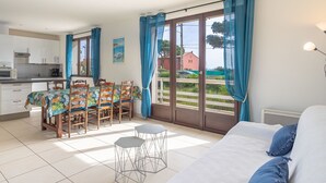Une pièce comprenant un lit, une table à manger avec des chaises, un coin cuisine et de grandes fenêtres avec des rideaux.