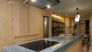 Una cocina moderna con armarios de madera, estufa integrada y encimera con lavamanos.