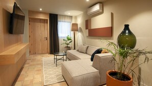 Una sala moderna con un sofá, una mesa de centro, una planta en maceta y un televisor de pantalla plana montado en la pared.