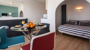 A modern living room with a glass dining table, a sofa, and a bed with striped bedding. - Les Brisants by Interhome (Quiberon)