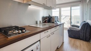 A modern kitchen with white cabinets, a wooden countertop, a built-in stove, and a coffee machine. - Les Brisants by Interhome (Quiberon)