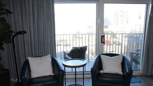 A room with two black leather chairs, a small round table, and a view of a balcony with a railing. - Steps to Boardwalk & Ocean! (Rehoboth Beach)