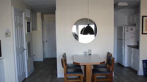 A dining area with a round mirror, wooden table, and four chairs. - Steps to Boardwalk & Ocean! (Rehoboth Beach)