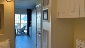 A hallway with a bed, a dresser, and a door leading to a balcony. - Steps to Boardwalk & Ocean! (Rehoboth Beach)