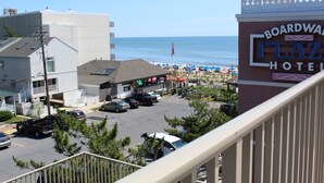 A view of Boardwalk Plaza Hotel with a parking lot, beach umbrellas, and a clear view of the ocean. - Fantastic Views of Ocean from the Extra-large Patio! (Rehoboth Beach)
