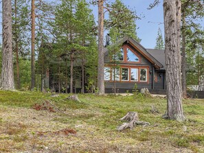 A cabin with a gabled roof, large windows, and surrounded by tall trees. - Vacation home Homma by Interhome (Raattama)