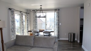 A living room with a grey sofa, a dining table with chairs, and a chandelier. - Spectacular Ocean View from Patio! (Rehoboth Beach)