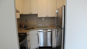 A kitchen with white cabinets, stainless steel appliances, and a granite countertop. - Spectacular Ocean View from Patio! (Rehoboth Beach)