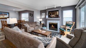 A modern living room with a fireplace, comfortable seating, and a dining area. - Blue Granite Off Main Townhome: Updated, Great Location (Frisco)